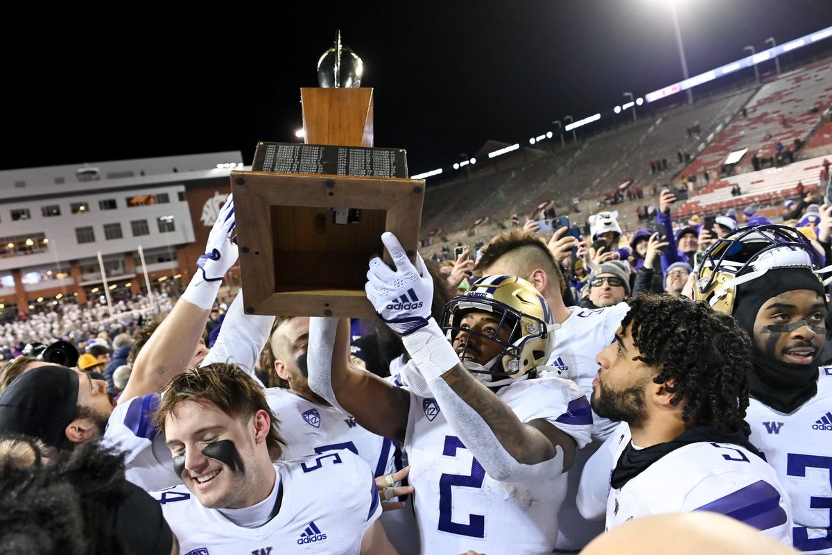 The Washington Huskies hoist the Apple Cup after defeating WSU during the second half of a college football game on Sunday, Nov. 27, 2022, at Martin Stadium in Pullman, Wash. The Washington Huskies won the game 51-33.  (Tyler Tjomsland/The Spokesman-Review)