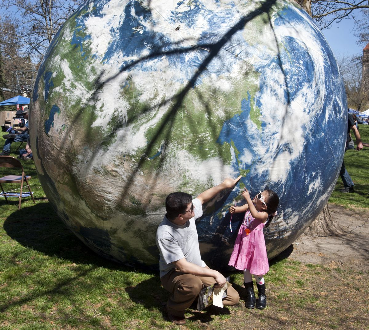 Ram Khadka shows his daughter, Roselyn, 3, a location along the coast of Japan as the pair visit Earth Day 2015 on Saturday in Spokane’s Riverfront Park. Khadka and his family are from Bhutan but are refugees from Nepal. (Dan Pelle)