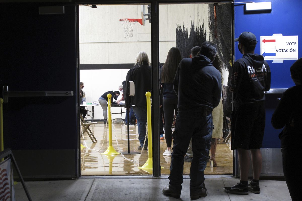 In this Nov. 3, 2020 photo, some of the last voters wait in line to cast their ballots after the line was cut off at 7 p.m., local time, outside the gymnasium at Reed High School in Sparks, Nev. Everyone in line when the polls closed at 7 p.m. was allowed to vote in Washoe County, where registration is split evenly between the two major parties in the northern part of the state. A new survey measuring the popularity of major pieces of sweeping legislation in Congress finds solid support from Americans for Democrats’ proposals to overhaul voting in the U.S. The Associated Press-NORC Center for Public Affairs Research poll found about half of Americans support expanding access to early and mail voting, while about 3 in 10 opposed the ideas and the rest had no opinion.  (Scott Sonner)