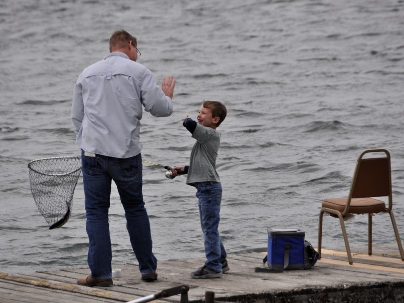 Quinn Connacher, 6, of Spokane celebrates catching his first trout while fishing off the dock at Bunker's Resort on Williams Lake with his stepfather, Andy Benson. They were fishing on April 28, 2013, the opening day of Washington's lowland trout fishing season. (Rich Landers)