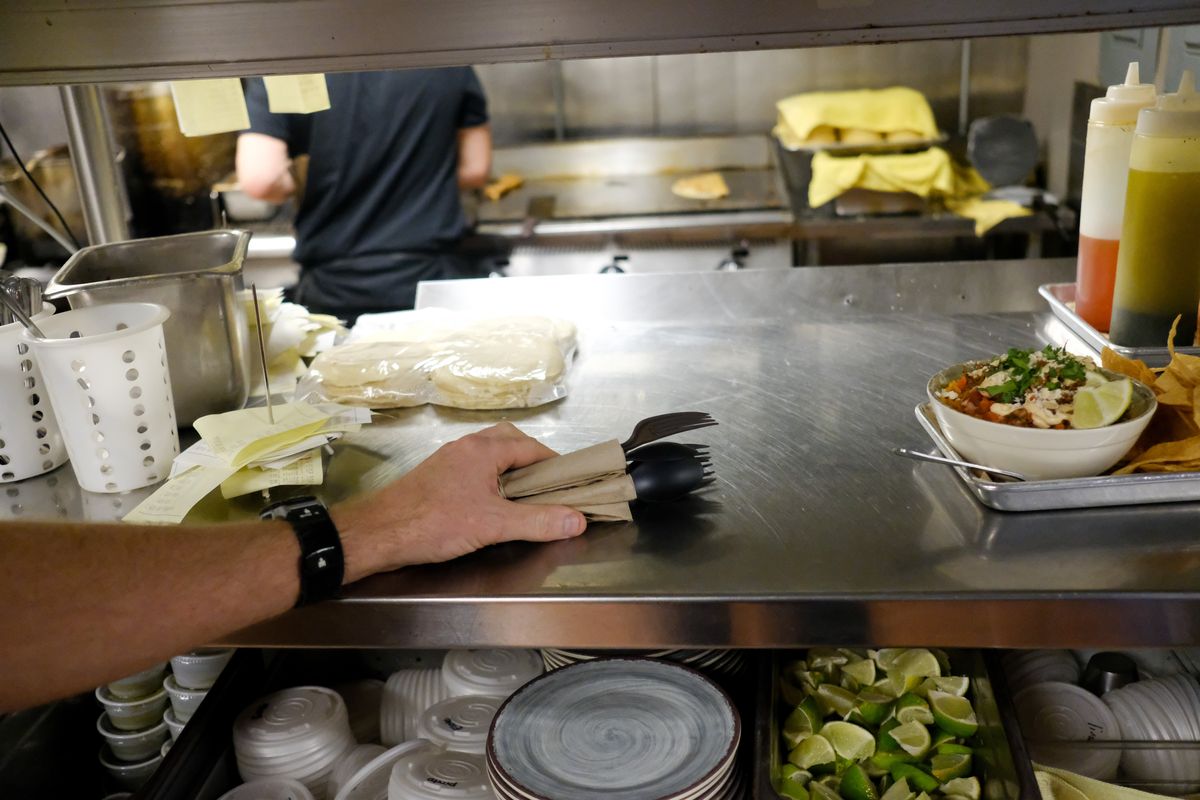 Justin Curtis, co-owner of Cochinito Taqueria, holds a selection of bio-degradable eating utensils in the kitchen of his restaurant Wednesday in Spokane.  (Tyler Tjomsland/The Spokesman-Review)