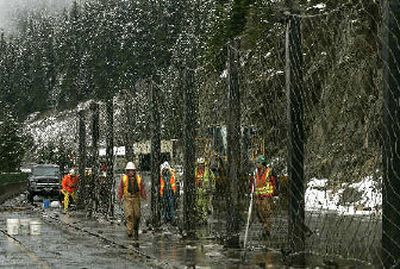 
Workers build a  fence designed to catch more falling rocks and give workers a safe place to work at a rockslide on Interstate 90 near Hyak, Wash., on Monday. The slide – and efforts to stabilize rocks on the hillside at right – closed the major route between Eastern and Western Washington  to traffic in both directions from early Sunday until late Monday, when one lane in each direction was reopened. 
 (Associated Press / The Spokesman-Review)