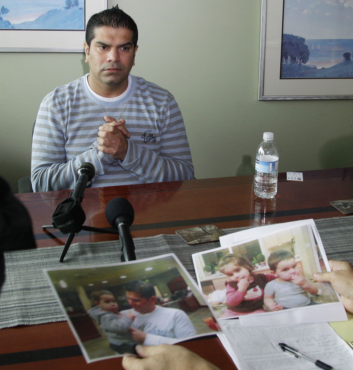 Solomon Metalwala talks to reporters in the office of his attorney, as photos of him and his two children are shown Monday in Bellevue. (Associated Press)