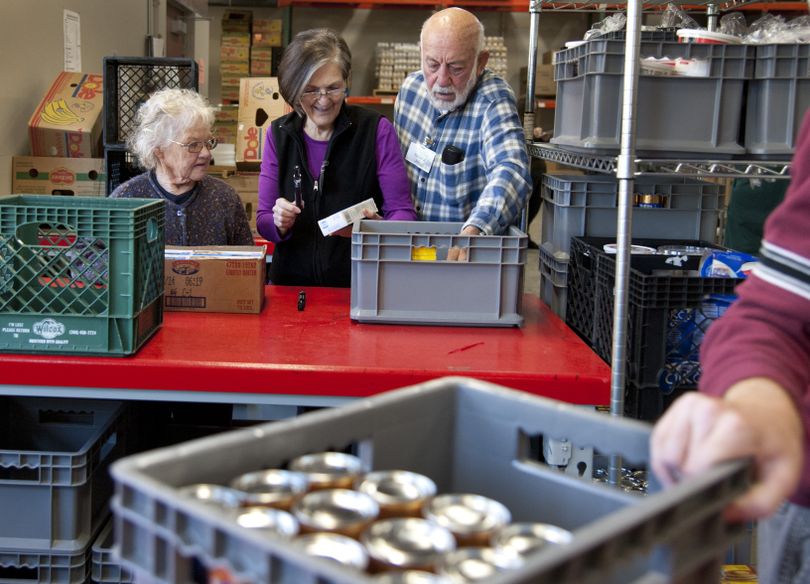 Volunteers Kathy McAteer, left, along with Kathy and John Malone sort through donated food on Tuesday at Spokane Valley Partners. (Dan Pelle)