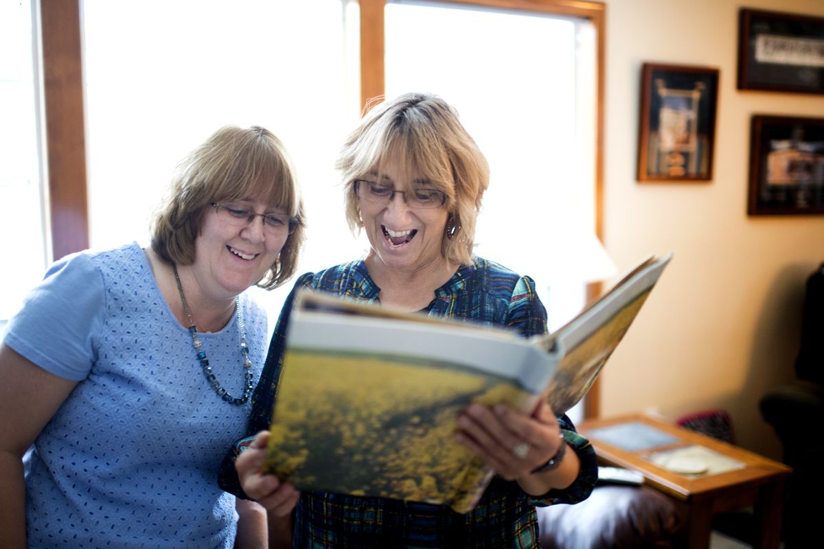 Patty Wiedmer and her sister Sandy Martin, daughters of Betty Stokes, look through family photos Thursday at Patty