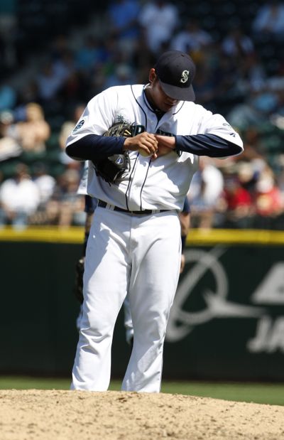 Seattle Mariners pitcher Felix Hernandez looks at his left wrist after being hit by a ball hit by Kansas City Royals 1B Eric Hosmer during the fourth inning of Sunday's game, a 7-6 for the M's (Associated Press)