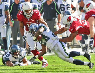 
Seattle cornerback Marcus Trufant intercepts a pass intended for Arizona's Larry Fitzgerald as teammate Jamie Sharper looks on back in November.
 (Associated Press / The Spokesman-Review)