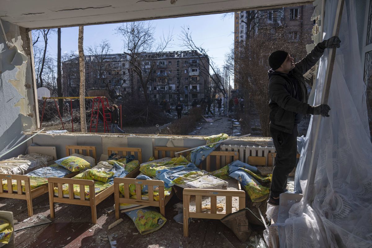 FILE - A man removes a destroyed curtain inside a school damaged among other residential buildings in Kyiv, Ukraine, Friday, March 18, 2022. As of early May, the Ukrainian government says Russia has shelled more than 1,000 schools, completely destroying 95.  (Rodrigo Abd)
