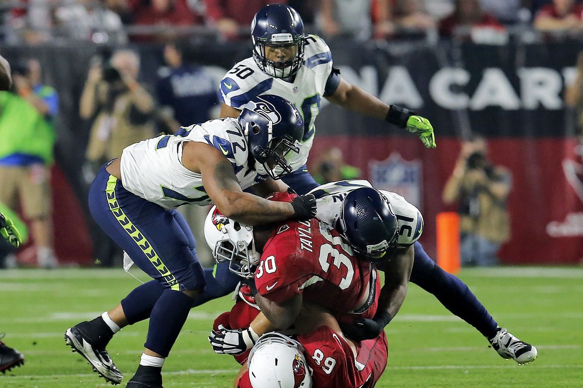 Cardinals running back Stepfan Taylor is buried by Michael Bennett, left, and Bruce Irvin of Seattle. Arizona had 29 yards rushing. (Associated Press)