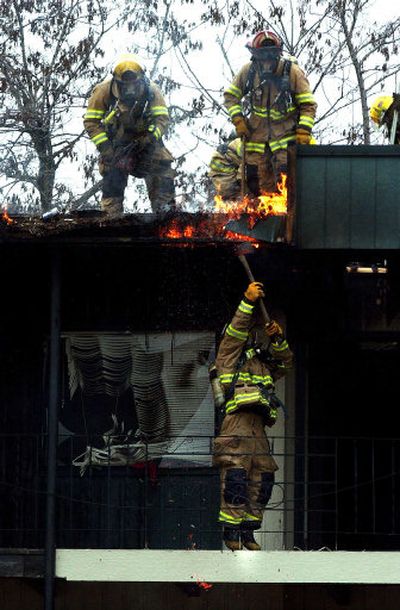 
Spokane firefighters work on the flames at an apartment house  on East Mission on Sunday. Nine families were displaced by the fire, which damaged several units.
 (Liz Kishimoto / The Spokesman-Review)