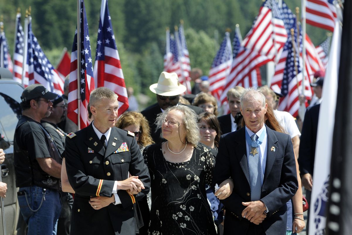 Heidy Baker, center, wife of Vernon Baker, walks back to the The Church of the Nazarene after military honors at an adjacent field escorted by Capt. David Darney, left, and Tom Norris, right.  Several hundred friends, family, dignitaries and neighbors gathered Saturday, July 31, 2010 to remember Vernon Baker as a WWII war hero and a westerner who loved to hunt and live in the woods. (Jesse Tinsley / The Spokesman-Review)