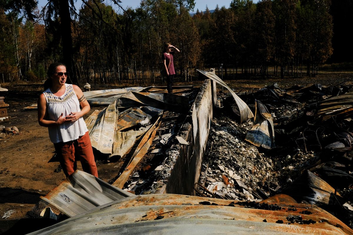 Maggie McComb and daughter Isabella look over the remains of their home Tuesday just north of Colville. It was destroyed earlier this month by the Crown Creek fire. (Tyler Tjomsland/The Spokesman-Review)