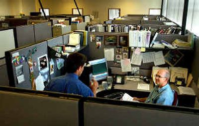 Planner Scott Kuhta, right, looks up from his work as Deputy City Attorney Cary Driskell, left, stops at his cubicle at Spokane Valley City Hall on Tuesday afternoon. The Spokane Valley City Council discussed moving City Hall out of Redwood Plaza.
(The Spokesman-Review)