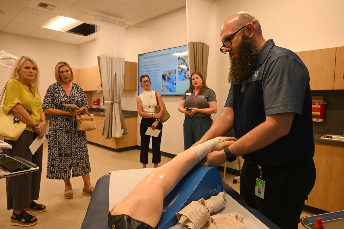 Clinical trainer Scott Martin, right, demonstrates the basics of wrapping bandages using a manikin arm at the open house for the new CHAS Learning Institute, which opened for tours Thursday in Spokane. The school will train prospective medical assistants, dental assistants and pharmacy technicians.  (Jesse Tinsley/THE SPOKESMAN-REVIEW)
