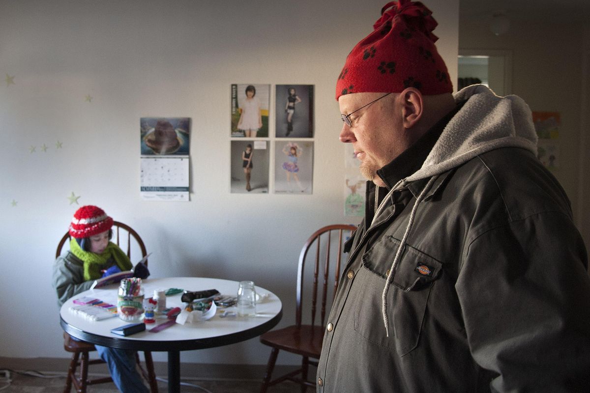 Matthew Watters, right, and his 9-year-old son Quercus bundle up for warmth in their darkened HUD apartment. The two live on a fixed income and are stretching their budget in the aftermath of the Nov. 17 windstorm.  (Dan Pelle / The Spokesman-Review)