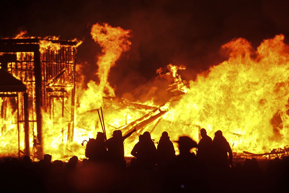 Attendees are silhouetted as the structure of the “Man” burns during Burning Man on Sept. 3, 2016 at the Black Rock Desert of Gerlach, Nev., north of Reno.  (Chase Stevens)