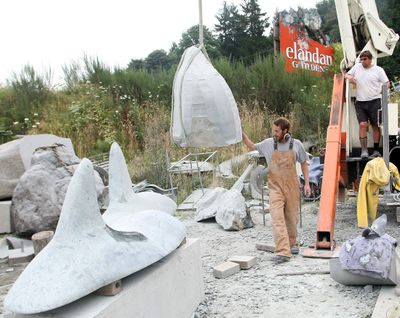 Colby Kenfield helps guide a rock orca head into position as he and artist Will Robinson, right, work on the four sculptures at Robinson’s studio at Elandan Gardens near Bremerton on Monday. (Associated Press)