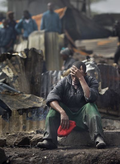 Joseph Mwangi, 34, sits in a state of shock after discovering the charred remains of two of his children at the scene of a fuel explosion Monday in Nairobi, Kenya. (Associated Press)