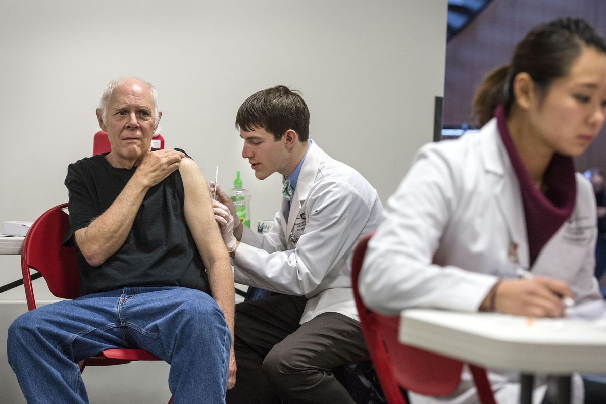 Washington State University College of Pharmacy student Peter Martsin administers a vaccination to Gary Thorne as student Sunao Tamuai completes paperwork on Friday during a free clinic for mumps vaccines in the basement of the Hemmingson Center on the Gonzaga University campus. (Dan Pelle / The Spokesman-Review)