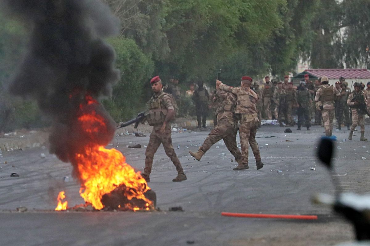 An Iraqi officer, center right, directs the soldier’s weapon to the weapon that was shooting to disperse anti-government protesters during a demonstration in Baghdad, Iraq, Sunday, Oct. 6, 2019. The protests began with demands for jobs and an end to corruption, and now include calls for justice for those killed in the protests. (Hadi Mizban / Associated Press)