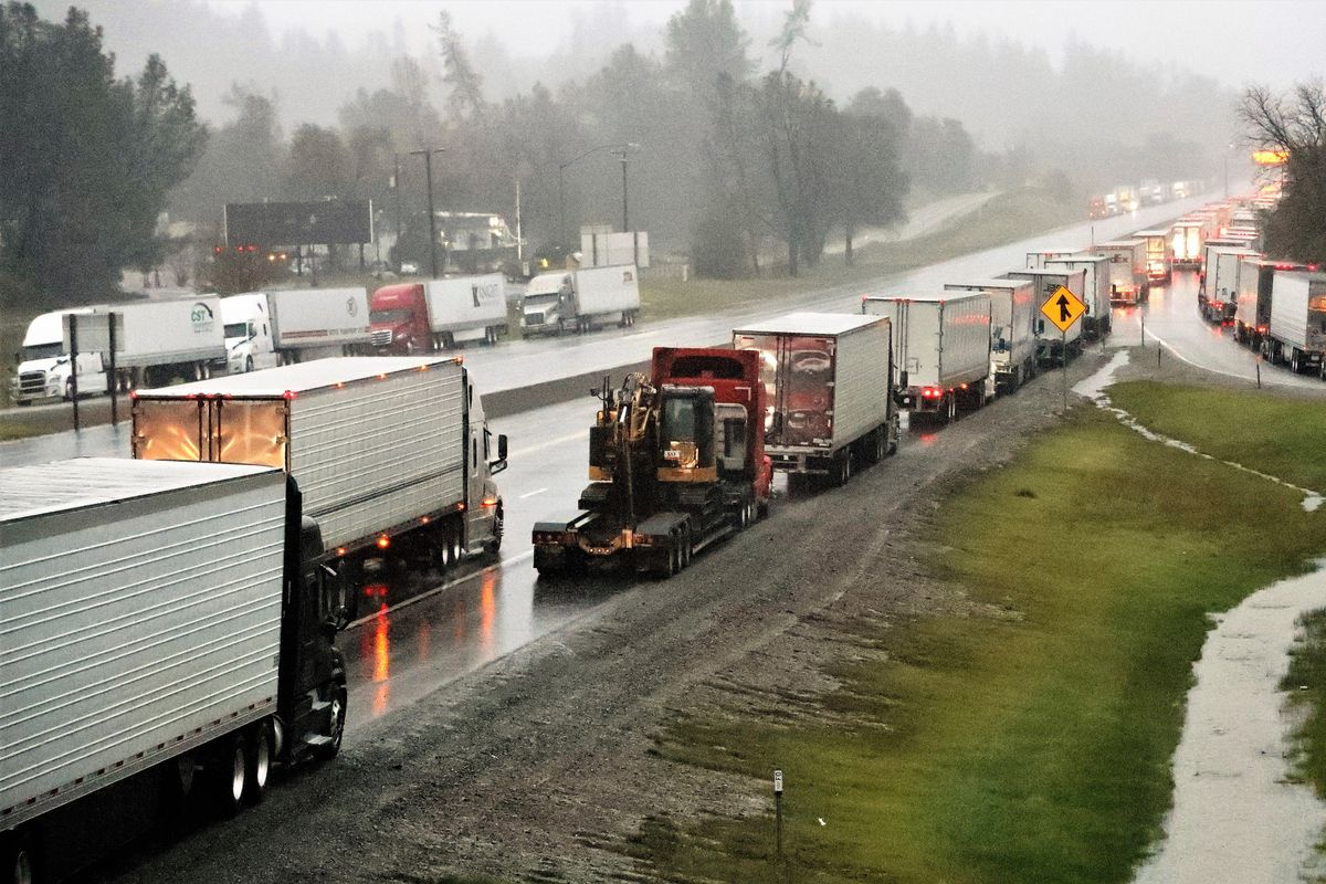 Dozens of semi-trucks sit parked along northbound Interstate 5 at Mountain Gate about 10 miles north of Redding, Calif., on Wednesday, Dec. 15, 2021. Heavy snow, blizzard conditions and stuck vehicles have prompted authorities to impose a shutdown of a portion of the West Coast