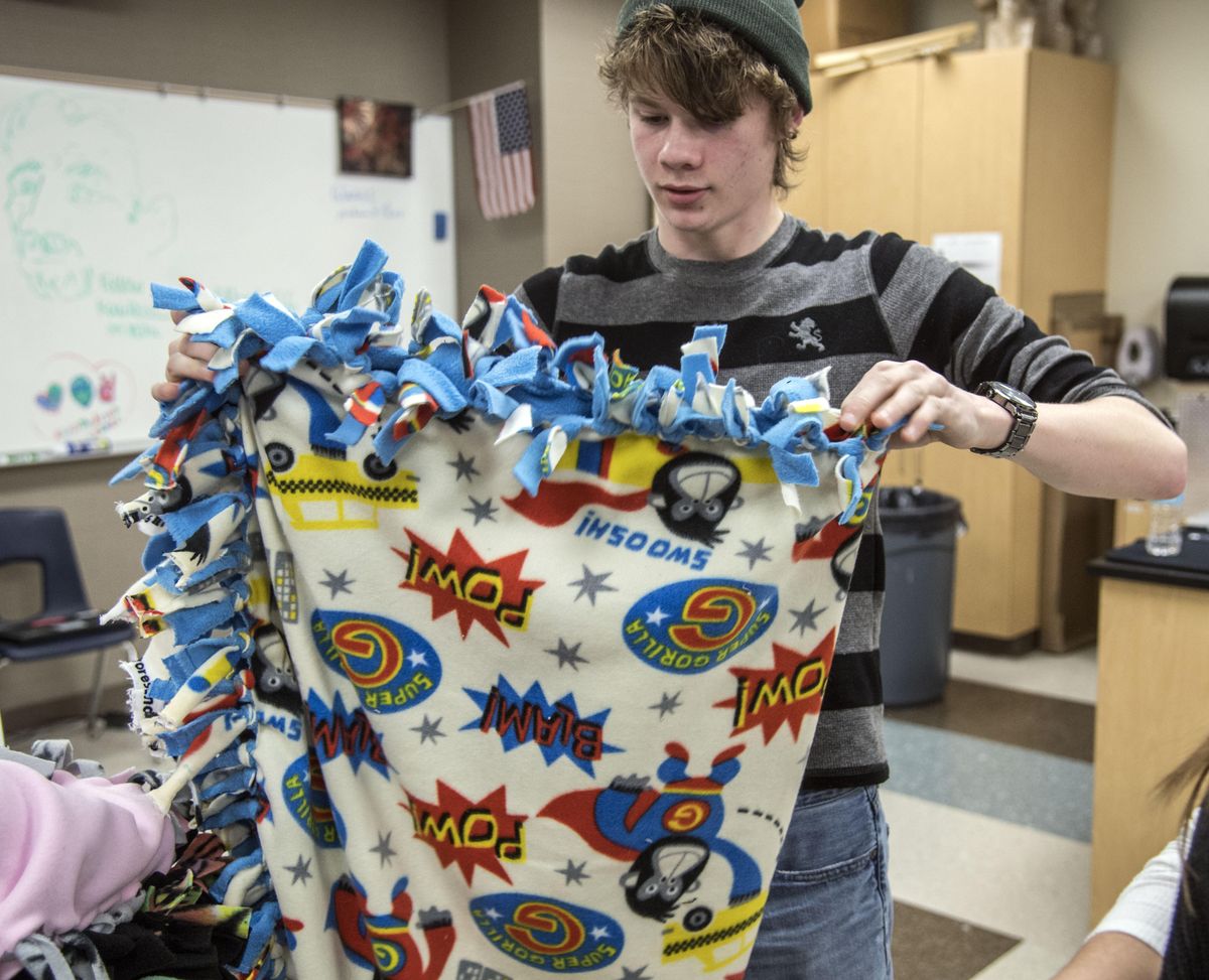On Track Academy student Jonathan Beach folds a blanket he helped create, Jan. 11, 2017. The blanket will go to CASA (Court Appointed Special Advocate) for children whose families are in crisis. Beach himself had  received quilts when he was a child in foster care. (Dan Pelle / The Spokesman-Review)