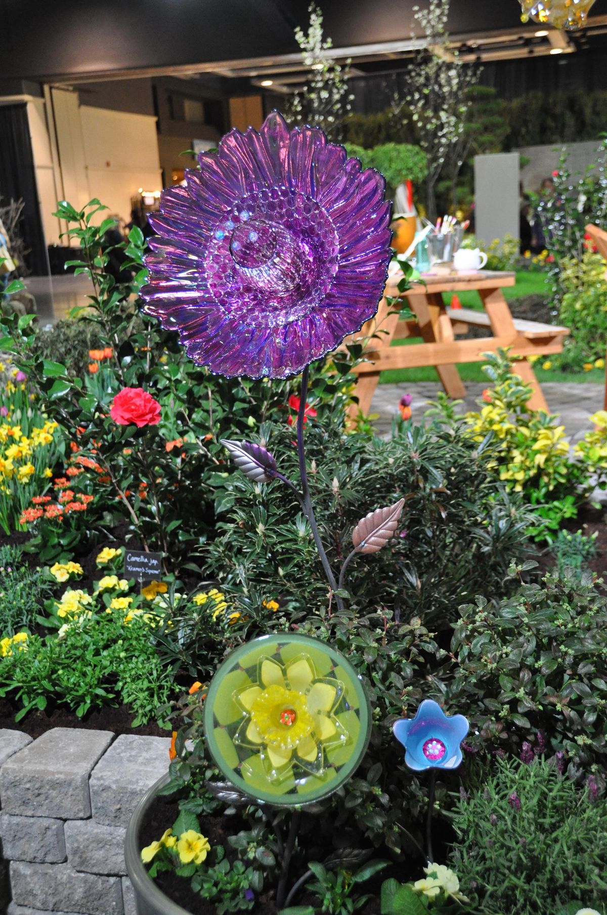 Purple, green and yellow glass ornaments light up a display garden at the Northwest Flower and Garden Show in Seattle. (Pat Munts / The Spokesman-Review)