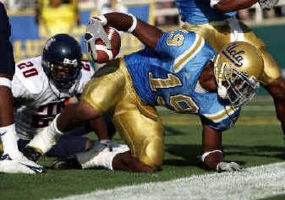 
UCLA tight end Marcedes Lewis (19) plows through the Arizona defense, including defensive back Lamon Means (20), for one of his three touchdowns Saturday. 
 (Associated Press / The Spokesman-Review)