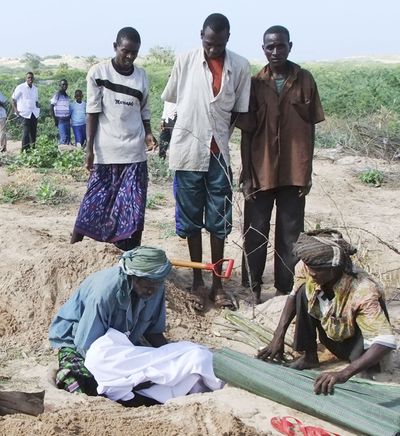 A man from southern Somalia lowers the body of a dead child into a grave in Mogadishu on Monday. (Associated Press)