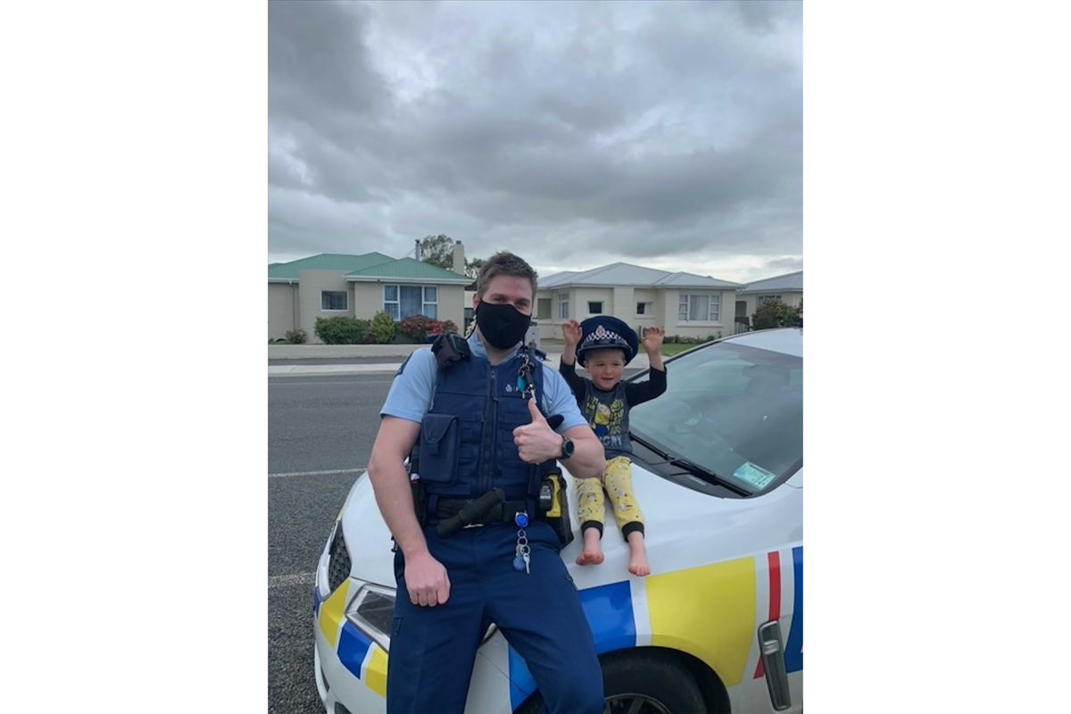 In this photo released by New Zealand Police, an officer identified only as Constable Kurt sits on his patrol car with a 4-year-old boy who is not identified, in the South Island city of Invercargill, New Zealand, Friday, Oct. 15, 2021. An emergency call made by the 4-year-old New Zealand boy asking for police to come over and check out his toys prompted a real-life callout and confirmation from an officer that the toys were, indeed, pretty cool.  (HONS)