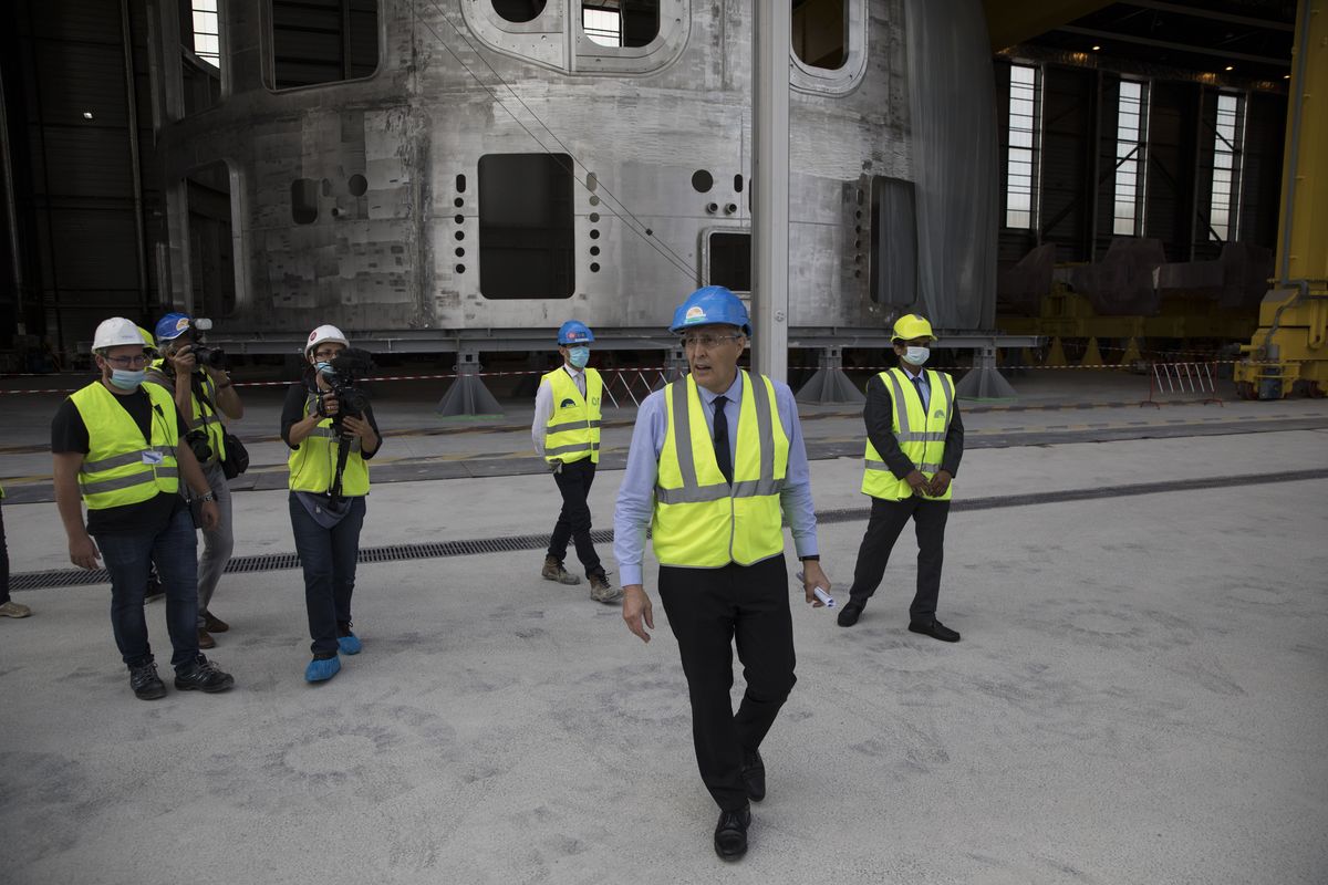 Director-General of the ITER Organization, Bernard Bigot walks by a portion of the cryostat meant for the assembly of the ITER Tokamak in the CEN of Cadarache, in Saint-Paul-Lez-Durance, southern France, Tuesday, July 28, 2020. A project of daunting proportions and giant ambitions replicating the energy of the sun is entering a critical phase as scientists and technicians begin piecing together massive parts built around the globe of a nuclear fusion device, an experiment aimed at showing that clean energy, free of carbon emissions, can keep our planet humming.  (Daniel Cole)
