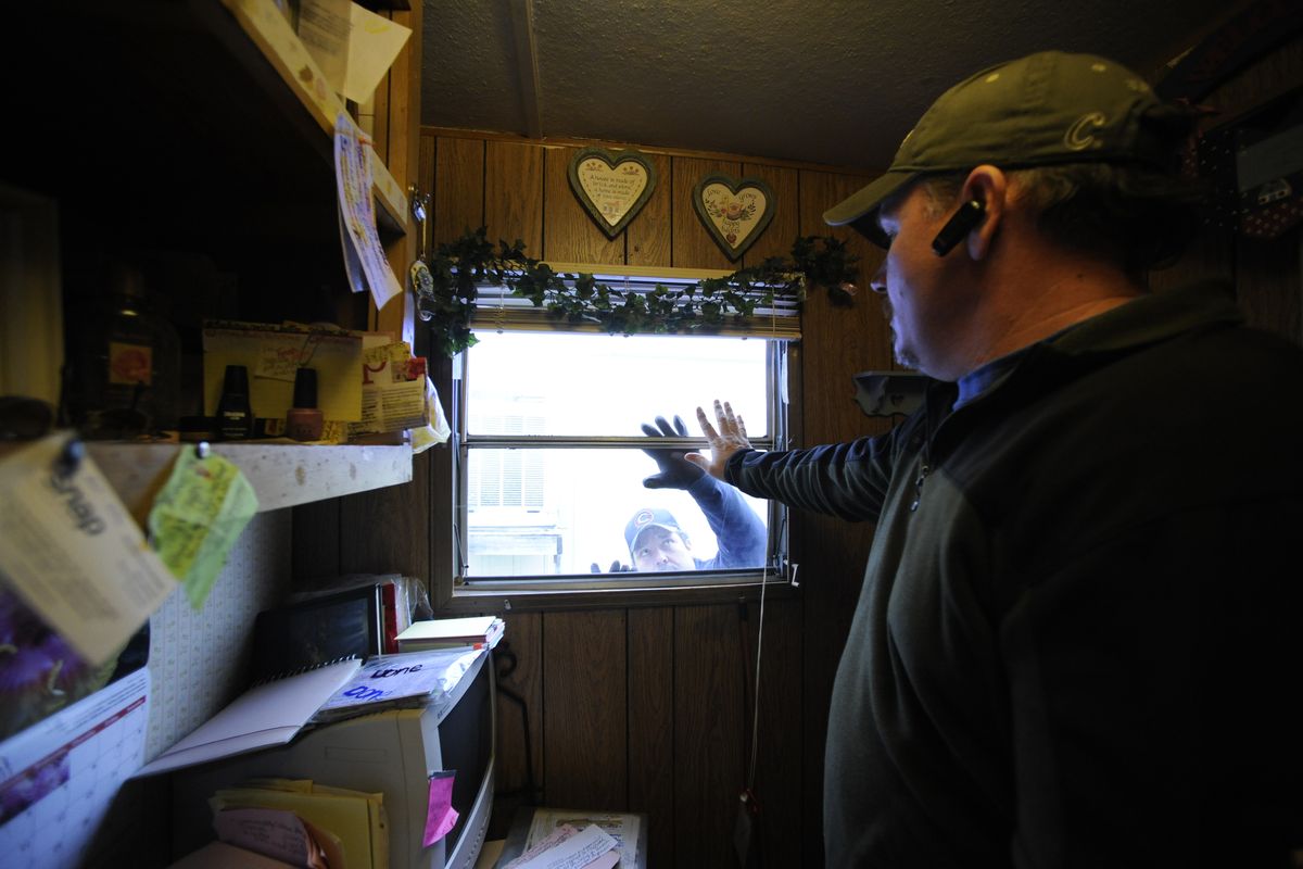 Mike Townsend, right, and Mario Ibarra, on the outside, work to seal a tip-out window on  Richard Hernandez’s mobile home in north Spokane, where SNAP was financing a weatherization project for the home Thursday.  (PHOTOS BY JESSE TINSLEY)
