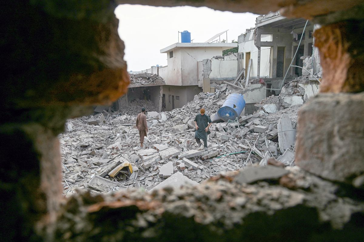 Locals stand on the debris of destroyed structures at the Government Health and Educational complex on Wednesday in Muridke, Pakistan. (Farooq Naeem)