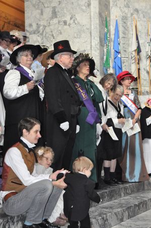Talcott Broadhead with daughters Clementine, age 5, and Henrietta, 15 months, gather on the steps of the Capitol Rotunda to mark the centennial of women getting the right to vote in Washington. Next to them is Darrell Holt (in top hat) and Carole Rambo Holt (green dress, Vote sash). (Jim Camden/Spokesman-Review)