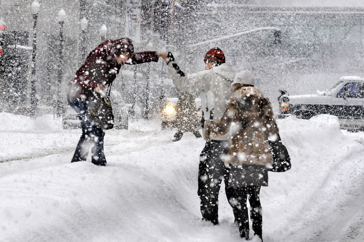 Olga Major,  Andrei Galynine and Yualiya Burdeyna, from left, make the leap across a berm in the middle of the west 900 block of Riverside Avenue during a heavy snowstorm over Spokane on Monday, Dec, 29, 2008.   (Christopher Anderson / The Spokesman-Review)