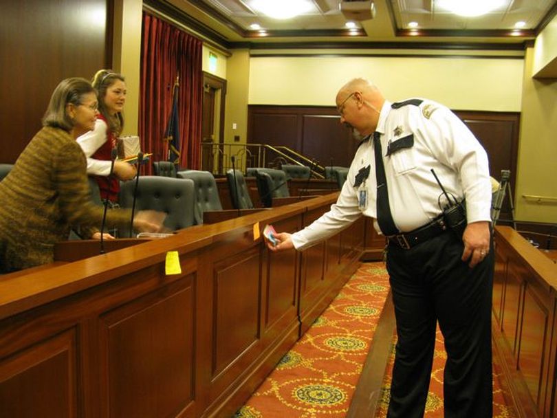 A Capitol security guard removes sticky notes from the dais after the 'Add The Words' print hearing on Friday. (Betsy Russell)