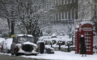 A woman  photographs a snow covered  taxi in London on Monday.   (Associated Press / The Spokesman-Review)