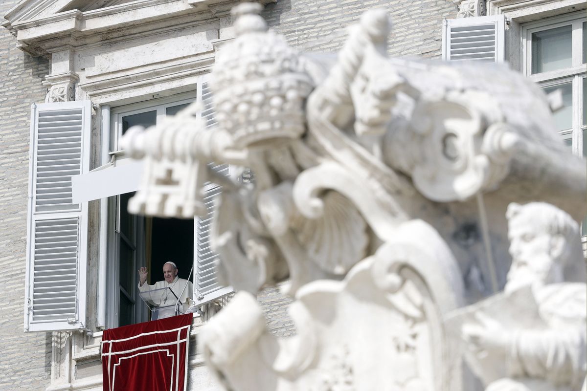 Pope Francis waves during the Angelus noon prayer delivered from his studio window overlooking St. Peter