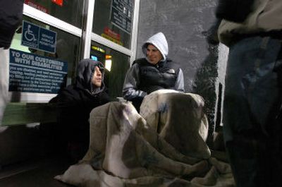 
Huddled under a blanket by the front doors with hundreds of others, Pete Vas Dias and Jason Shadrick await the 5 a.m. Friday opening of the Post Falls Wal-Mart. 
 (Photos by Jesse Tinsley/ / The Spokesman-Review)