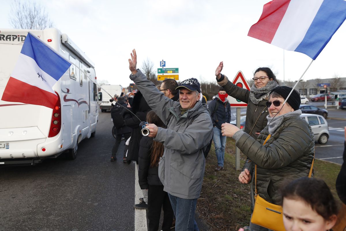 People wave to a convoy departing for Paris, Friday, Feb.11, 2022 in Strasbourg, eastern France. Authorities in France and Belgium have banned road blockades threatened by groups organizing online against COVID-19 restrictions. The events are in part inspired by protesters in Canada. Citing "risks of trouble to public order," the Paris police department banned protests aimed at "blocking the capital" from Friday through Monday. (Jean-Francois Badias)