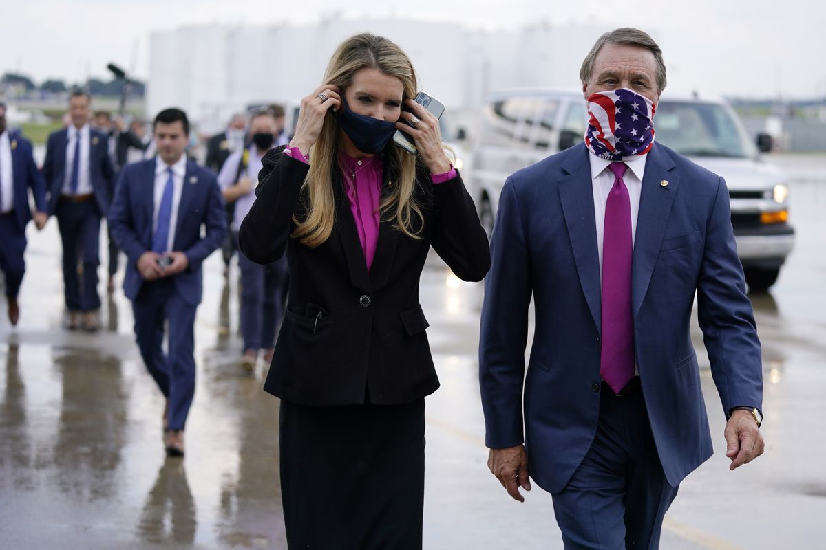 Sen. Kelly Loeffler, R-Ga., puts on a face mask as she walks with Sen. David Perdue, R-Ga., at UPS Hapeville Airport Hub in Atlanta in July.  (Evan Vucci)