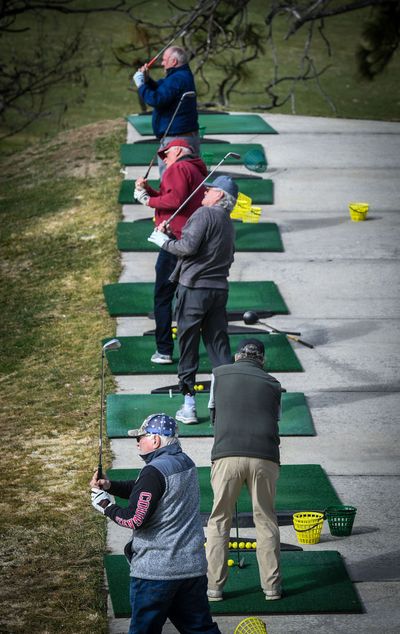 Golfers fill the tee box mats and take practice swings at the Downriver Golf Course driving range before heading to golf carts and onto the course, Wednesday morning in Spokane. Downriver opened for the season last Friday.  (DAN PELLE/THE SPOKESMAN-REVIEW)