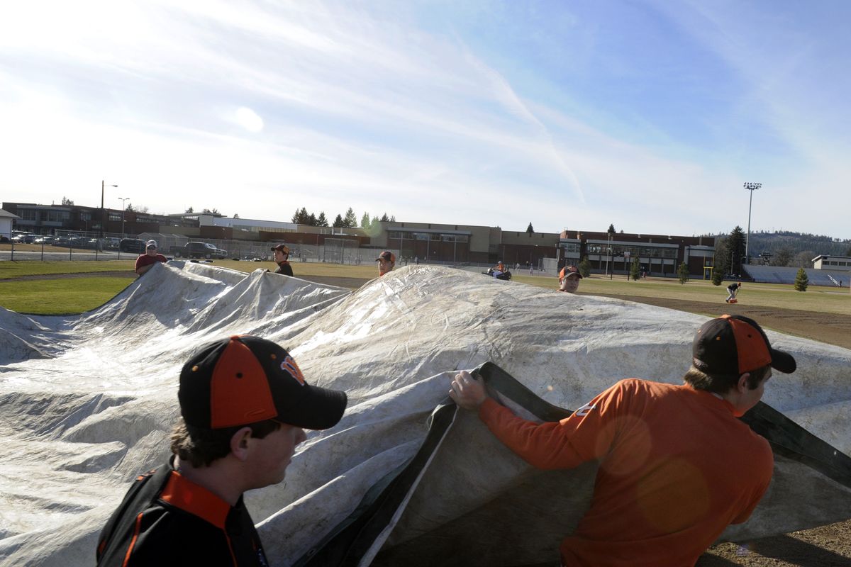 West Valley players pull the tarp off the batters box before the first day of practice Monday. “This is my 10th year at West Valley,” said head coach Don O’Neal, “and this is the first time we’ve been able to get out on our own field the first day.” (J. BART RAYNIAK)