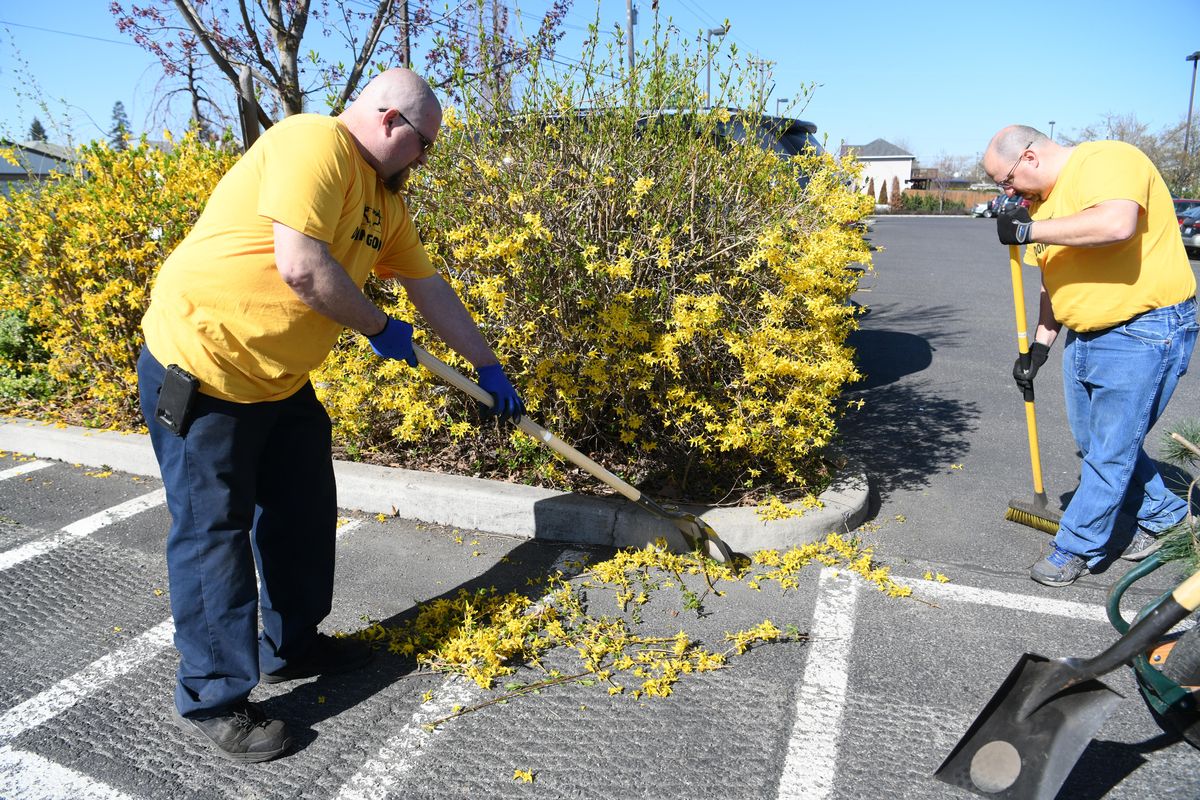 Auto technician Jerry Brown, left, and parts specialist Andrew Tate from the Larry H. Miller dealerships clean up around the Northeast Community Center Thursday, April 26, 2018, as part of their day of service. (Jesse Tinsley / The Spokesman-Review)