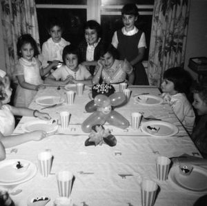 Carol Willette’s 8th birthday party in November 1962. She’s in front of the cake with her hand on her cheek. Cleda Sweetland is on the left side of the photo with the bow in her hair and a watch on her wrist.