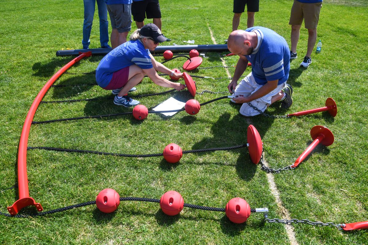 Blaine Hawley, left, and Tom Smith, both from Maryland, work to assemble pieces of the SwiggleKnots Bridge, Tuesday, July 9, 2019, as part of the of a community service project for the National Association of Elementary School Principals Conference. Over 100 of the nationÕs school principals spent the morning building a playground and sprucing up the school. (Dan Pelle / The Spokesman-Review)