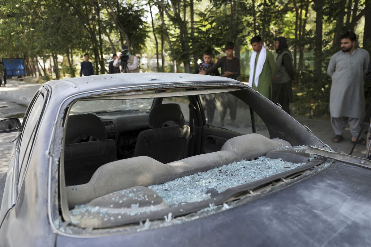 Afghan men look at a damage car after a roadside bomb explosion in Kabul, Afghanistan, Sunday, June 6, 2021.  (Rahmat Gul)