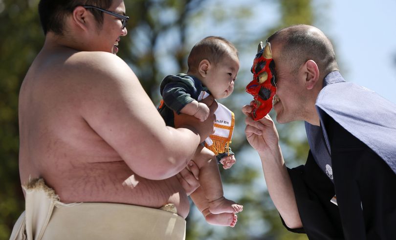 A referee puts an ogre mask to make a baby, who is held by a college sumo wrestler, cry to win in the Naki Sumo, or crying baby contest at Sensoji Buddhist temple in Tokyo, Friday, April 29, 2016. The babies participated in the annual traditional ritual performed as a prayer for healthy growth of them. (Eugene Hoshiko / Associated Press)