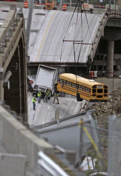 
Workers remove a school bus from the collapsed bridge on Sunday. All 52 children aboard survived the accident.Associated Press
 (Associated Press / The Spokesman-Review)