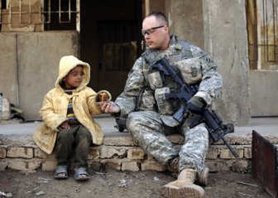 
Army Staff Sgt. William Lambert, 30, from Plainview, Ark., shares rations with an boy in Beijia, a village south of Baghdad, on Monday. Associated Press
 (Associated Press / The Spokesman-Review)